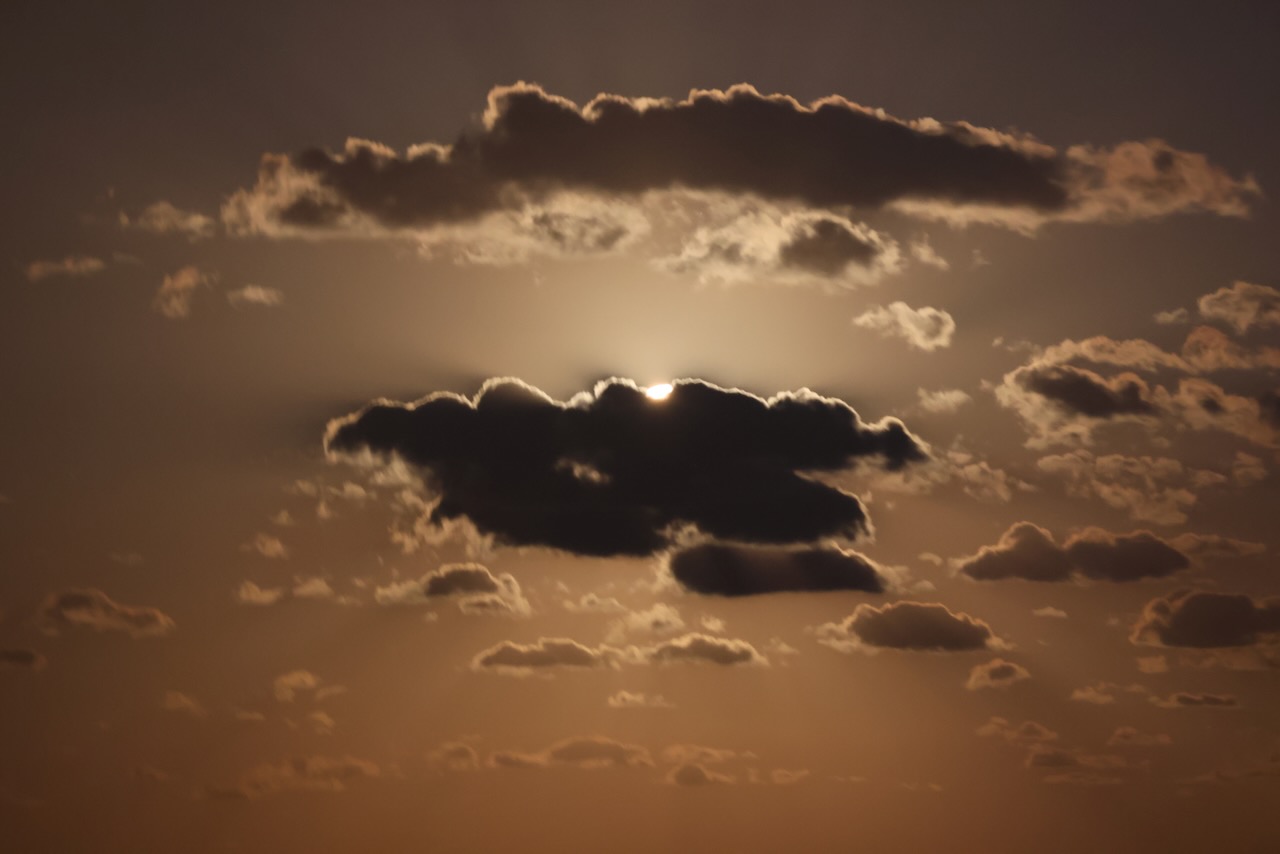 Dark clouds silhouetted against an amber-colored sky.